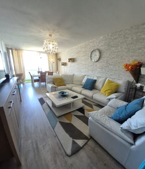 Salon moderne avec canapé sectionnel beige, tapis géométrique et baies vitrées du sol au plafond dans l'appartement Val'Déco, Les Ponts de