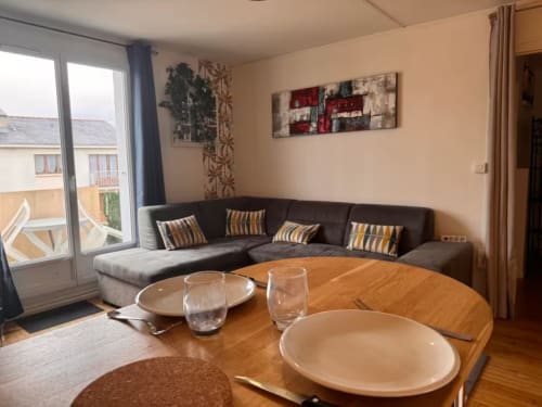 Séjour moderne avec canapé noir, table de salle à manger en bois et vue sur balcon à Val'Déco Conciergerie, Les Ponts de Cé