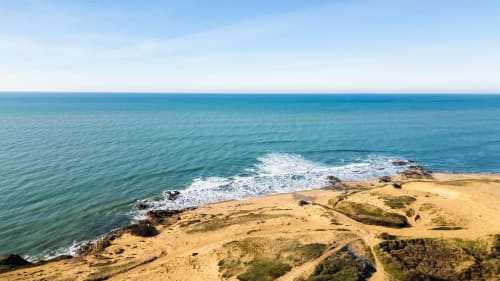 Vue pittoresque des falaises côtières avec plage de sable, eaux turquoise et vagues blanches près de Les Ponts de Cé, France