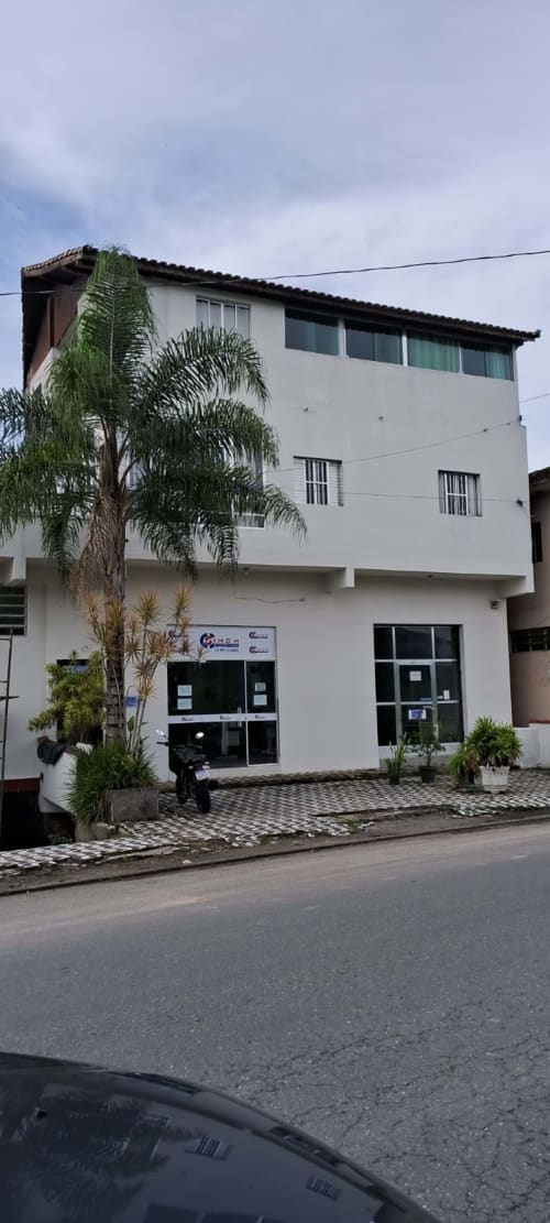 Pousada Serra Azul, um edifício de apartamentos branco com 3 andares em Juquiá, com palmeira e entrada no térreo.