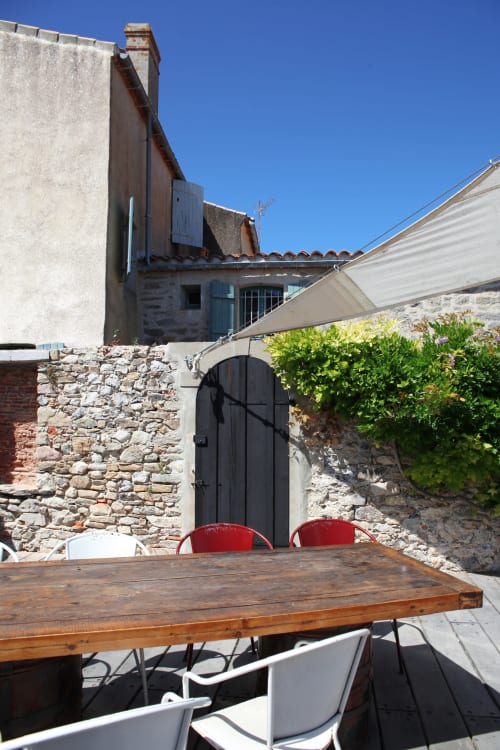 Terrasse extérieure avec table en bois et chaises rouges à Val'Déco Conciergerie, Les Ponts de Cé