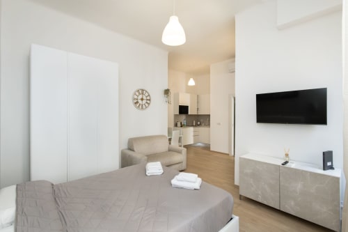 Modernes Studioapartment in Mailand mit Bett, Sofa, Küchenzeile und wandmontiertem TV in offener Grundrissgestaltung