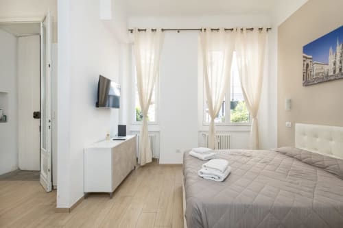 Helles Schlafzimmer in den Magnolia Apartments Mailand mit Doppelbett, Schreibtisch, TV und Gartenblick durch Fenster