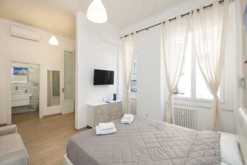 Helles Schlafzimmer in Mailänder Wohnung mit Queensize-Bett, Flachbildfernseher, eigenem Bad und Sheer-Vorhängen mit Gartenblick