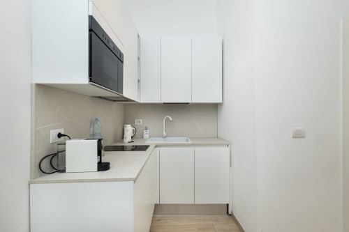 Modernes weißes Küchenette in Magnolia Apartments Mailand mit Herd, Spüle, Mikrowelle und Edelstahlofen