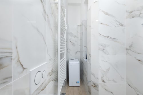 Modernes Waschzimmer mit Marmorfliesen in den Magnolia Apartments Mailand mit weißer Waschmaschine und Handtuchhalter