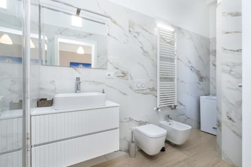 Modernes Badezimmer in den Magnolia Apartments Mailand mit Marmorwänden, Aufsatzwaschbecken, Toilette, Bidet, beheizter Handtuchhalter und