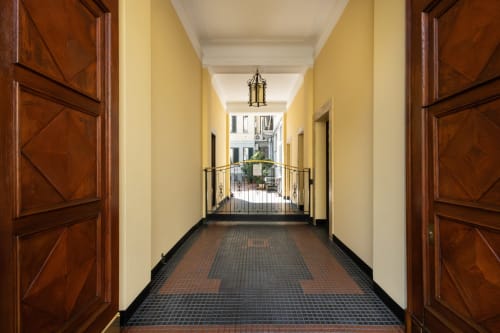 Eleganter Flur im Magnolia Apartments Mailand mit Holztüren, gelben Wänden und Fliesenbodenöffnung zum Innenhof