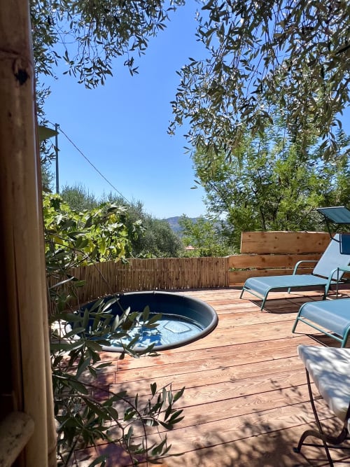 Terrasse en bois à l'Agritusmo Stecadò avec jacuzzi, transats, oliviers et vue sur les montagnes à Dolceacqua