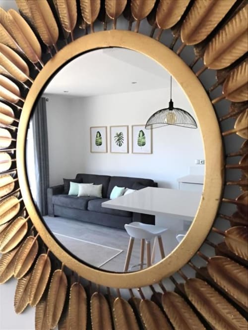 Gold sunburst mirror reflecting modern living room with dark sofa at Sweet Holiday, Porto-Vecchio apartment