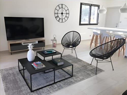 Séjour moderne à Sweet Holiday à Porto-Vecchio avec mobilier noir, télévision, fauteuils ronds et décoration minimaliste