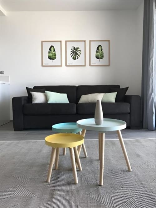 Modern living room with black sofa, colorful side tables, and botanical wall art at Sweet Holiday apartment in Porto-Vecchio