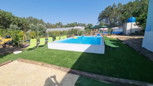 Resort pool with bright blue water, green lounge chairs, and manicured lawn at Charm Discovery Quinta da Oliveirinha villa in