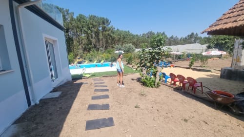 Espaço de jardim exterior em Casa da Oliveirinha com piscina, cadeiras vermelhas e pinheiros em Leiria, Portugal