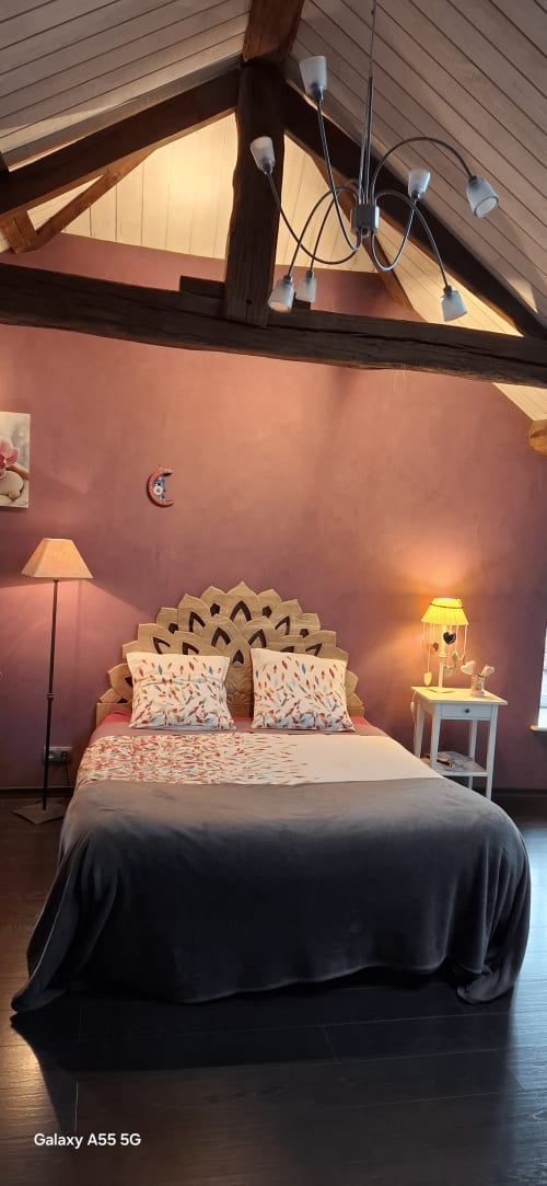 Chambre mansardée douillette à La Maison de Marie-Claire avec murs en terre cuite, poutres en bois et vue sur le jardin
