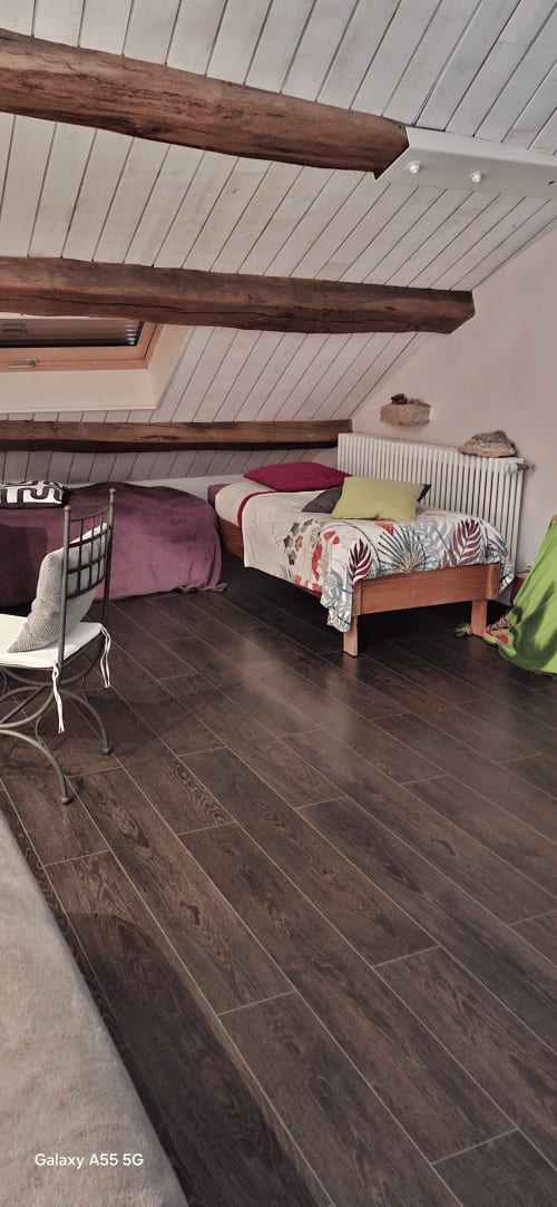 Chambre mansardée à La Maison de Marie-Claire avec poutres apparentes, parquet foncé et lits jumeaux aux draps colorés