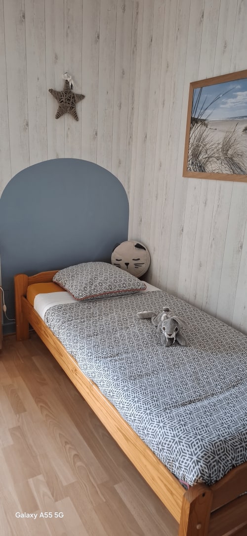 Chambre cosy à La Maison de Marie-Claire avec lit en bois, parure patterned, tête de lit bleue et décoration étoile de mer