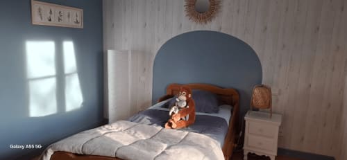 Chambre douillette à La Maison de Marie-Claire B&B avec lit en bois, mur bleu et vue sur le jardin à Doncourt-sur-Meuse