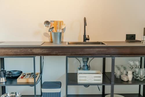 Piano cottura moderno nell'appartamento della cascina Tenuta Alela con lavello, rubinetto, portautensili e ripiani aperti sottostanti