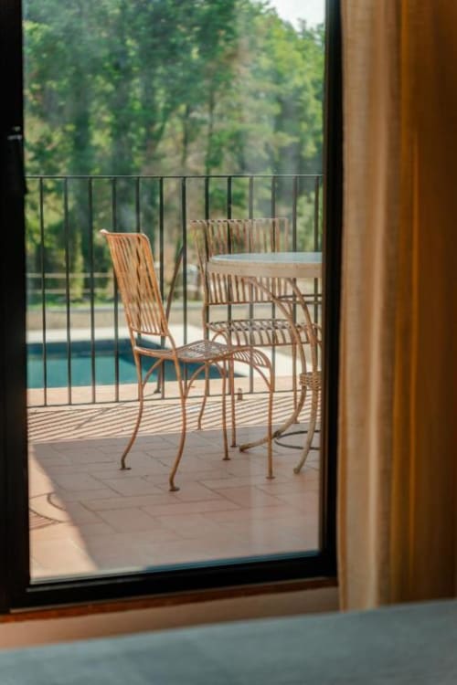 Vista dal balcone dell'Aparthotel Camino presso Tenuta Alela con sedie in legno, piscina e paesaggio giardino toscano a Figline Valdarno