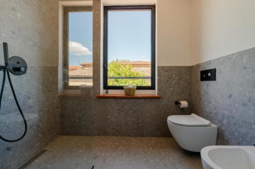 Bagno moderno nell'appartamento della stalla Tenuta Alela, Figline Valdarno, con wc sospeso, doccia e vista sul giardino