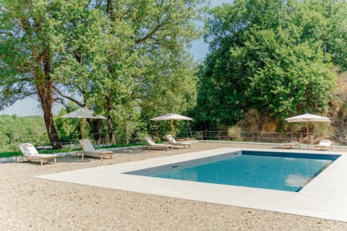 L'area piscina di Tenuta Alela a Figline Valdarno con sdraio, ombrelloni e alberi maestosi