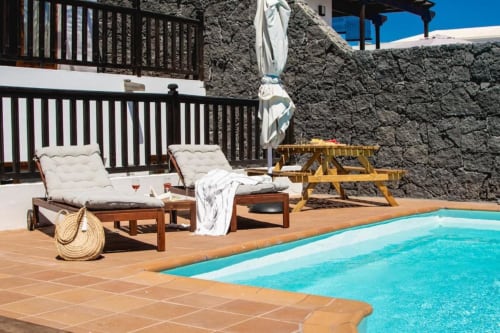 Terraza junto a la piscina de Villa Cavendish con tumbonas, piscina turquesa y muros de piedra en Playa Blanca