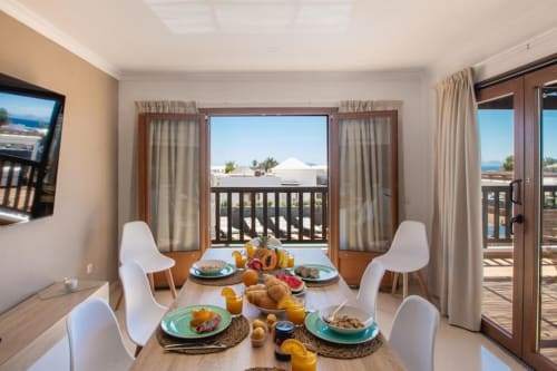 Comedor de Villa Cavendish en Playa Blanca con vistas al océano, sillas modernas y desayuno servido