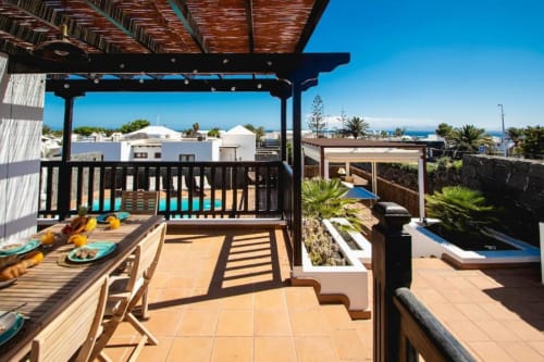 Terraza Villa Cavendish en Playa Blanca con vistas al mar, zona de comedor, pérgola y piscina