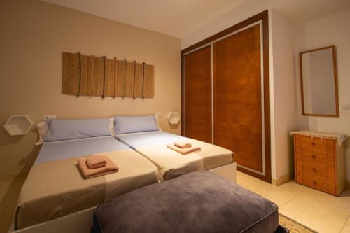 Dormitorio moderno en Villa Cavendish con camas gemelas, armario de madera y toques en terracota en Playa Blanca