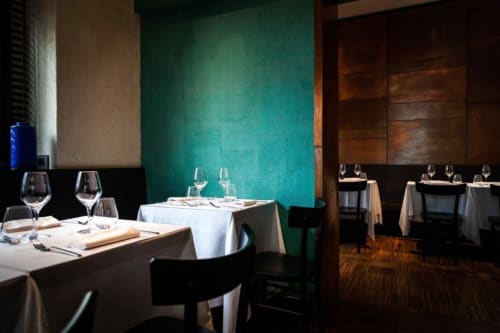 Elegante sala da pranzo di Porta Tosa Milano con pareti turchesi, tovaglie bianche e mise en place formali
