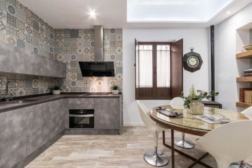Cocina moderna y comedor en Loft Gracia de CTH Granada con azulejos decorativos, electrodomésticos negros y muebles de madera