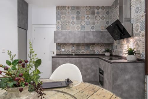 Cocina moderna en loft de CTH Granada con azulejos decorativos, gabinetes grises, zona de comedor y flores frescas