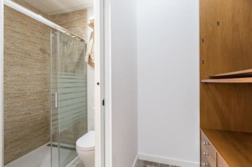 Baño moderno en el apartamento loft CTH Granada Gracia con ducha de cristal, azulejos en paredes, inodoro y armario de madera