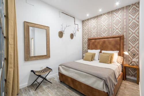 Dormitorio moderno en CTH Granada Loft Gracia en Armilla con cama tapizada marrón, papel pintado estampado y espejo de madera