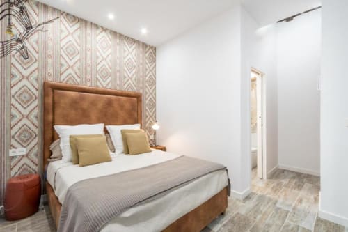 Dormitorio moderno en el apartamento CTH Granada Loft Gracia, Granada, con cabecero de cuero tostado, pared de acento con patrón y