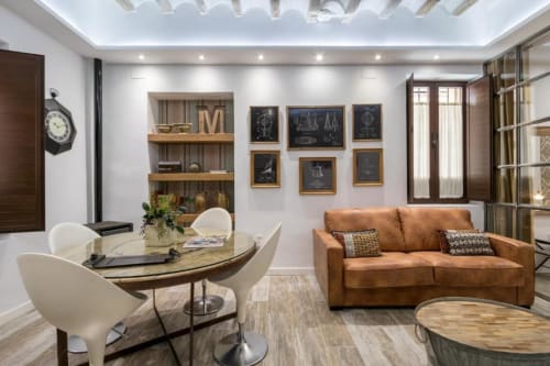 Moderno apartamento loft en CTH Granada con sofá de cuero cognac, zona de comedor, estantería empotrada y decoración contemporánea