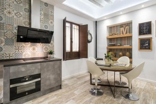 Moderno espacio de cocina-comedor en Loft Gracia de CTH Granada con azulejos decorativos, campana negra, mesa de comedor y madera