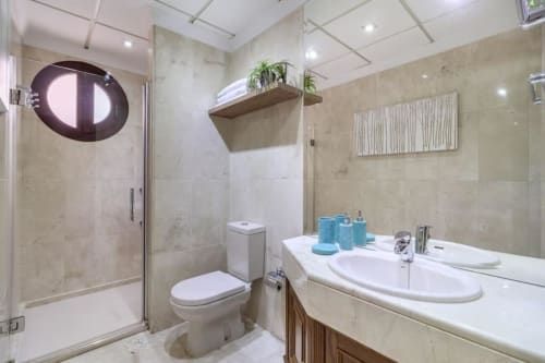 Baño moderno del apartamento CTH Granada con lavamanos doble, ducha, inodoro y estantería decorativa con plantas en Armilla