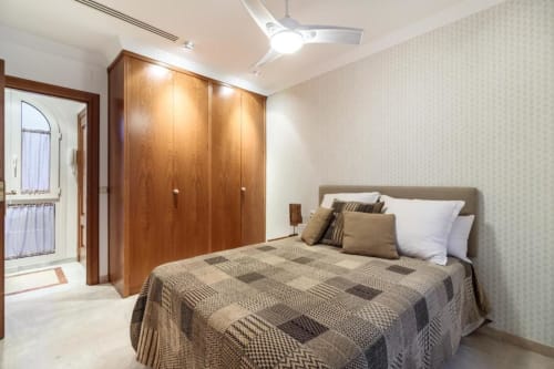 Dormitorio moderno en el Green Apartment del hotel CTH Granada en Armilla, con armarios de madera, ropa de cama estampada y vistas a la ciudad