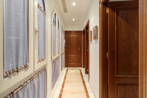 Pasillo moderno del apartamento CTH Granada en Armilla con puertas de madera, iluminación empotrada y suelos de baldosa