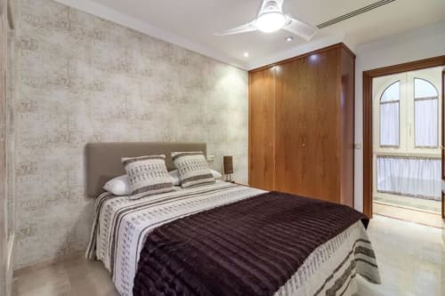 Moderno dormitorio en CTH Granada Green Apartment, Armilla con armario de madera, ropa de cama estampada y vistas a la ciudad desde el balcón