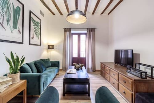Moderna sala de estar en Green Apartment CTH Granada con sofá turquesa, vigas de madera, TV y vistas a la ciudad desde el balcón