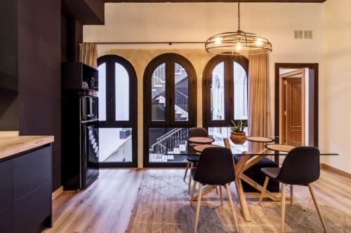 Comedor moderno en apartamento CTH Granada con puertas arqueadas, mesa de madera, sillas negras y vistas a la ciudad desde el balcón