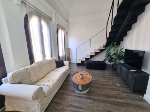 Amplia sala de estar del Ático Gracia con sofá color crema, mesa de centro de madera y escalera negra en apartamento de hotel en Granada