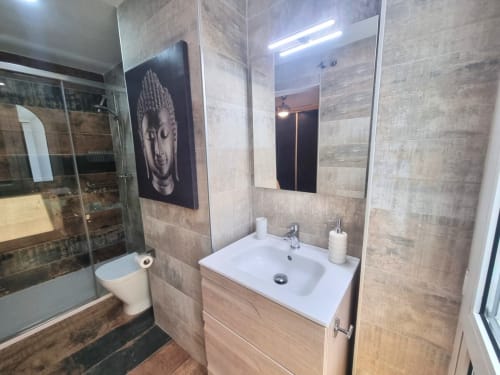 Baño moderno en el Penthouse CTH Granada Gracia con lavamanos blanco, espejo grande, iluminación LED y detalles en madera y baldosa