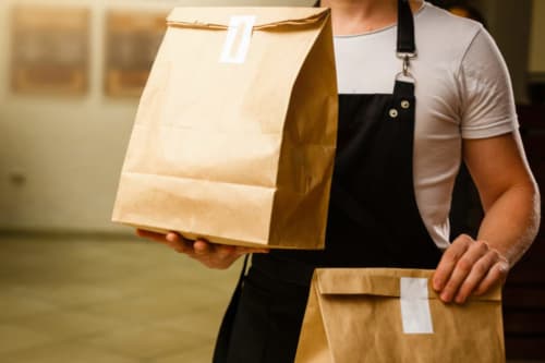 Membro dello staff con borse di carta kraft per consegne presso la struttura Porta Tosa bed and breakfast a Milano