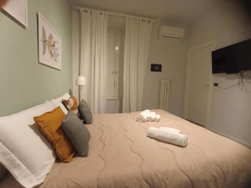Camera accogliente con letto matrimoniale, cuscini decorativi e TV a parete presso AD Trastevere Guest House a Roma