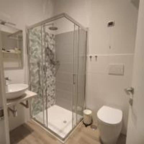 Bagno moderno nella struttura AD Trastevere Guest House con doccia in vetro, toilette bianca e piastrelle beige, Roma
