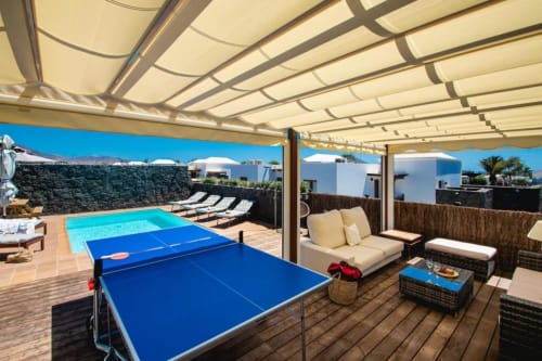 Terraza Villa Cavendish en Playa Blanca con mesa de ping pong, piscina, zona de descanso y vistas al mar